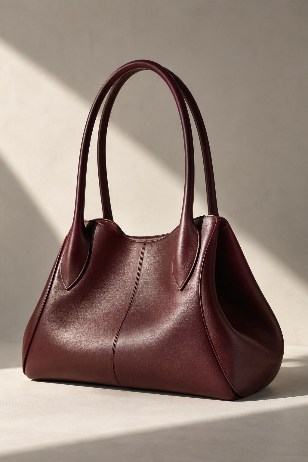 Original product study: a sculptural burgundy leather handbag in directional daylight